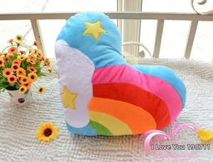 Detailed plush pillow with rainbow color segments and yellow star embroidery on white rug