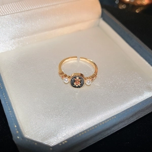 Detail of vintage gold-plated ring with black enamel center and delicate side pearls