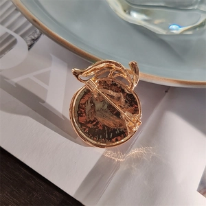 Close-up of the golden round brooch back with a secure pin clasp and hammered texture