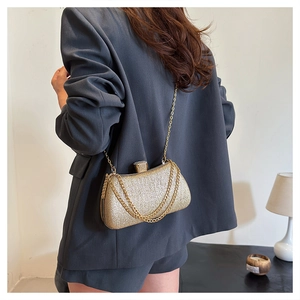Detailed view of golden evening clutch with diamond clasp and metal chain on grey blazer
