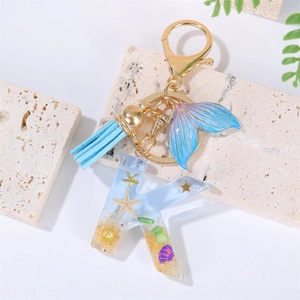Detail of blue ocean-themed resin letter K keychain with starfish and shell elements