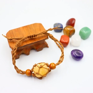 Macro detail of hand-woven brown wax rope bracelet with yellow raw stone and wooden beads