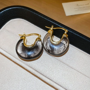 Gros plan détaillé des boucles d'oreilles rétro en résine en U sur un plateau à bijoux