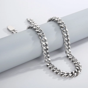 Close-up of hip hop silver Cuban chain necklace with buckle on minimalist grey stand