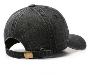 Detail view of washed denim baseball cap featuring an adjustable bronze metal buckle