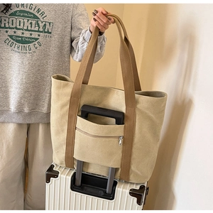 Detail of khaki canvas tote bag with functional luggage strap and rear zipper pocket