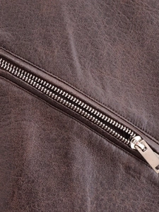 Macro shot of dark brown faux leather texture and premium silver metal zipper detail