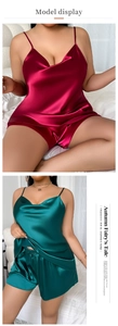 Close-up of satin camisole set showing glossy deep red and dark green silk texture