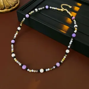 Detail of colorful beaded necklace with freshwater pearls and gold heart pendant