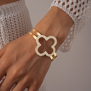 Dettaglio di un bracciale a quadrifoglio dorato con strass indossato da una modella