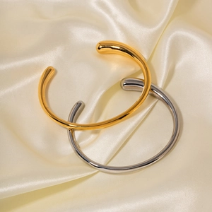 Detailed view of minimalist gold and silver open bangles with high-polished mirror finish