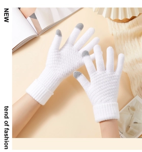 Detail of white knit touchscreen gloves showing grey fingertips and ribbed cuffs on a desk