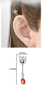 Detailed view of skull bow earrings with cross and red teardrop gemstone pendants
