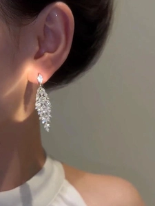 Macro shot of silver tassel earrings with marquise-cut zircons worn by a female model