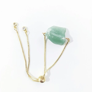 Detail of adjustable gold box chain bracelet with irregular raw green crystal stone