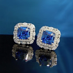 Royal blue princess cut stud earrings with marquise halo setting on black mirror reflection