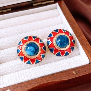 Macro detail of vintage resin earrings with red and blue sunburst design in a jewelry box