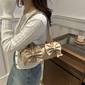 Elegant beige bow shoulder bag for women with two decorative bows in a stylish indoor setting