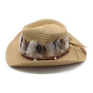 Detail of wide brim straw hat with ethnic feathers, woven bands and metal charms