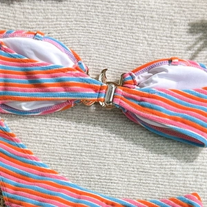 Detail of striped bikini top with textured fabric and golden metal bow buckle