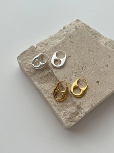 Detailed macro view of chunky gold and silver hollow oval hoop earrings on stone