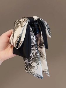 Détail de la pince à cheveux avec nœud à motif floral et longs rubans bicolores