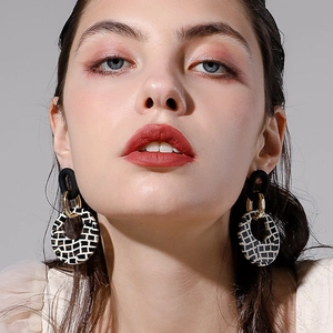 Gros plan d'un mannequin portant des boucles d'oreilles géométriques à carreaux noirs et blancs