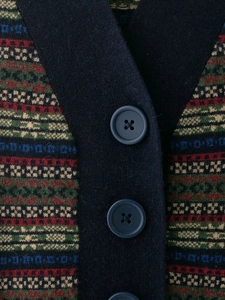 Dettaglio macro del gilet in maglia retrò con bottoni blu scuro e motivo a rombi