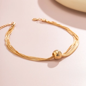 Detail of multi-strand gold snake chain bracelet featuring a polished ball bead