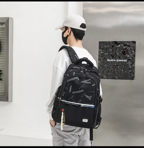 Detailed view of black waterproof backpack with white lettering and yellow strap tag