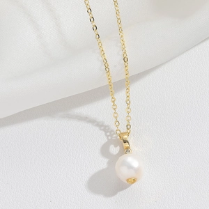 Detailed macro view of an elegant crown pearl pendant on an 18K gold chain necklace