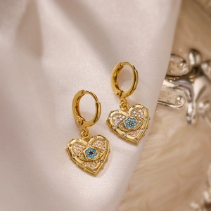 Gold plated evil eye heart earrings with white and blue stones on white silk background