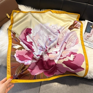 Carré de soie aux motifs floraux et bordure jaune sur un tapis en fausse fourrure blanche