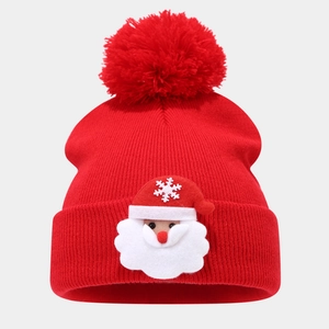 Detail of red Christmas knit beanie with pom-pom and Santa Claus embroidery patch