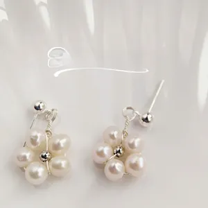 Macro detail of elegant flower-shaped earrings featuring natural freshwater pearls and silver beads