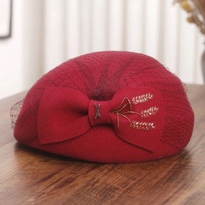 Close-up of wool beret with mesh veil, bead-embroidered bow, and fine texture