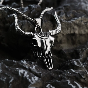 Vintage stainless steel necklace featuring a large bull skull pendant on dark rock surface