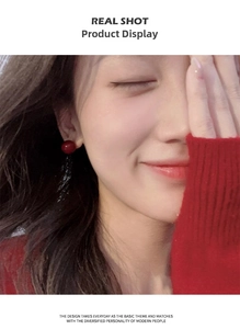 Close-up of elegant red spherical stud earrings worn by model with matching red sweater