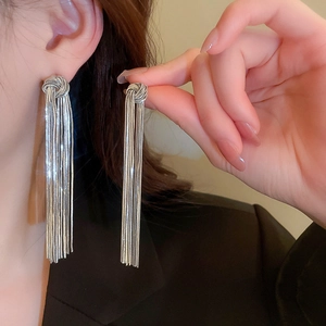 Silver flower bow tassel drop earrings with long metal chains worn by a model