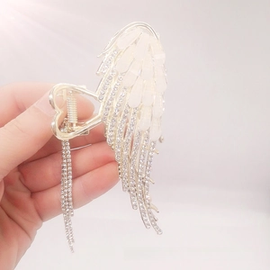 Detailed close-up of golden angel wing hair claw with rhinestones and long tassels