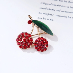 Detail of red cherry brooch with green enamel leaves and sparkling crystal accents