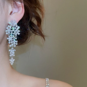 Silver flower tassel earrings with clear cubic zirconia worn by a model on side profile