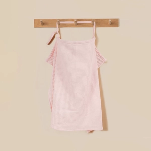 Close-up of pink cotton waffle nursing cover with soft texture on a wooden hook