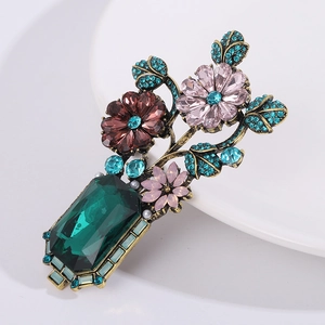 Vintage Baroque floral brooch with emerald green crystal and pink rhinestones on white plate
