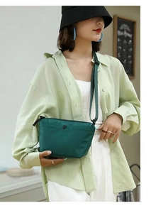 Detail of dark green nylon dumpling crossbody bag with adjustable strap and zip closure