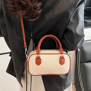 Chic two-tone canvas and brown leather Boston bag with top handles and shoulder strap