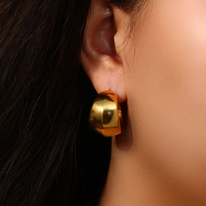 Gros plan d'un mannequin portant une boucle d'oreille géométrique en or 18 carats poli