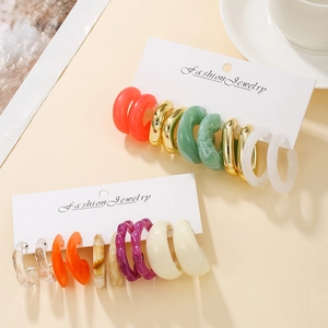 Detailed view of colorful acrylic and metal C-shaped hoop earrings on display cards