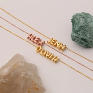 Dettaglio di tre collane personalizzate con nomi in finitura oro rosa e oro