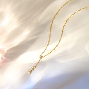 Detail of gold Y-shaped S925 silver necklace with four vertical diamonds on silk